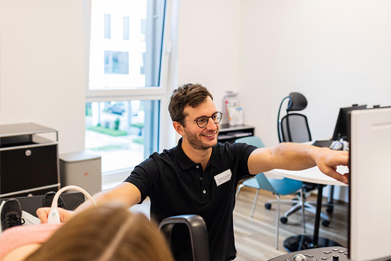 Gefaessklinik Tsantilas Arzt untersucht Patient mit einem Ultraschallgerät und zeigt auf dem Bildschirm