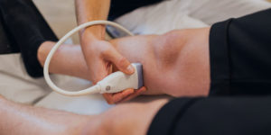 Venenleiden Gefaessklinik Tsantilas Patient wird mit einem Ultraschallgerät am Bein untersucht